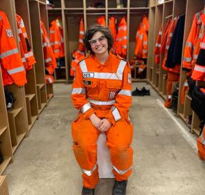Volunteer Amanda Meuwissen in orange uniform, sitting and smiling at the camera. 